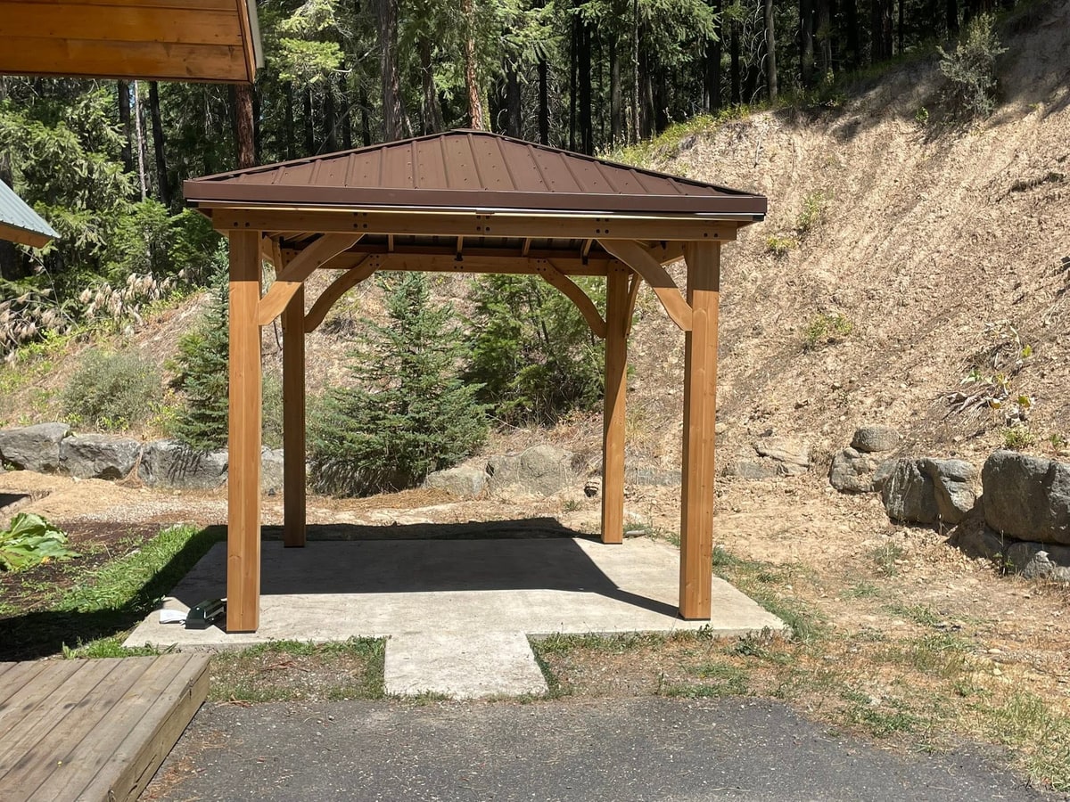 Timber gazebo on a concrete pad by a deck.