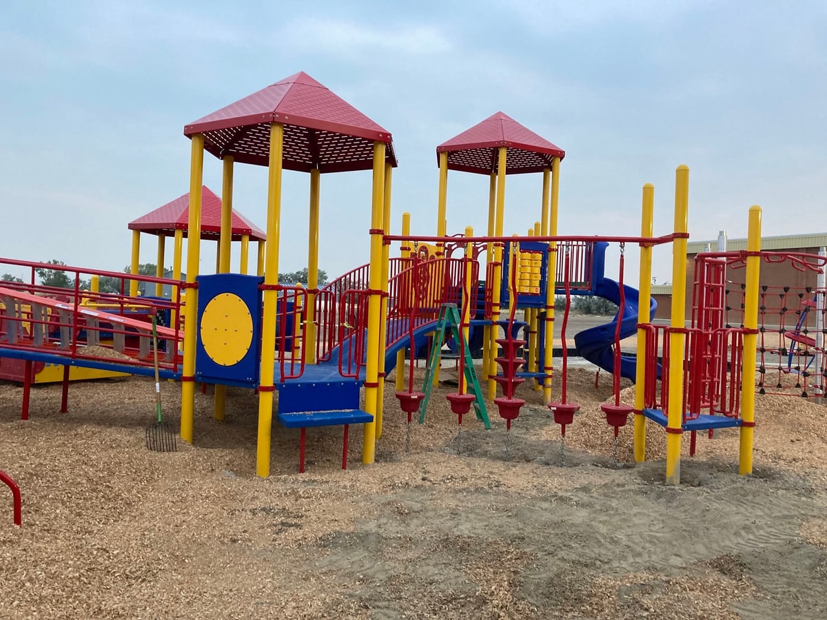 Red-roofed towers with monkey bars on wood chips.