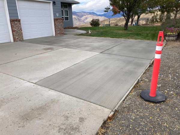 New driveway section with a traffic cone, mountains beyond.
