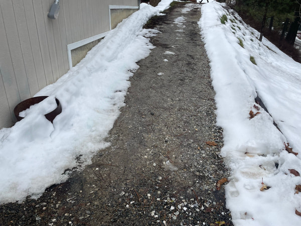 Snow-lined dirt path beside the house before the walkway.