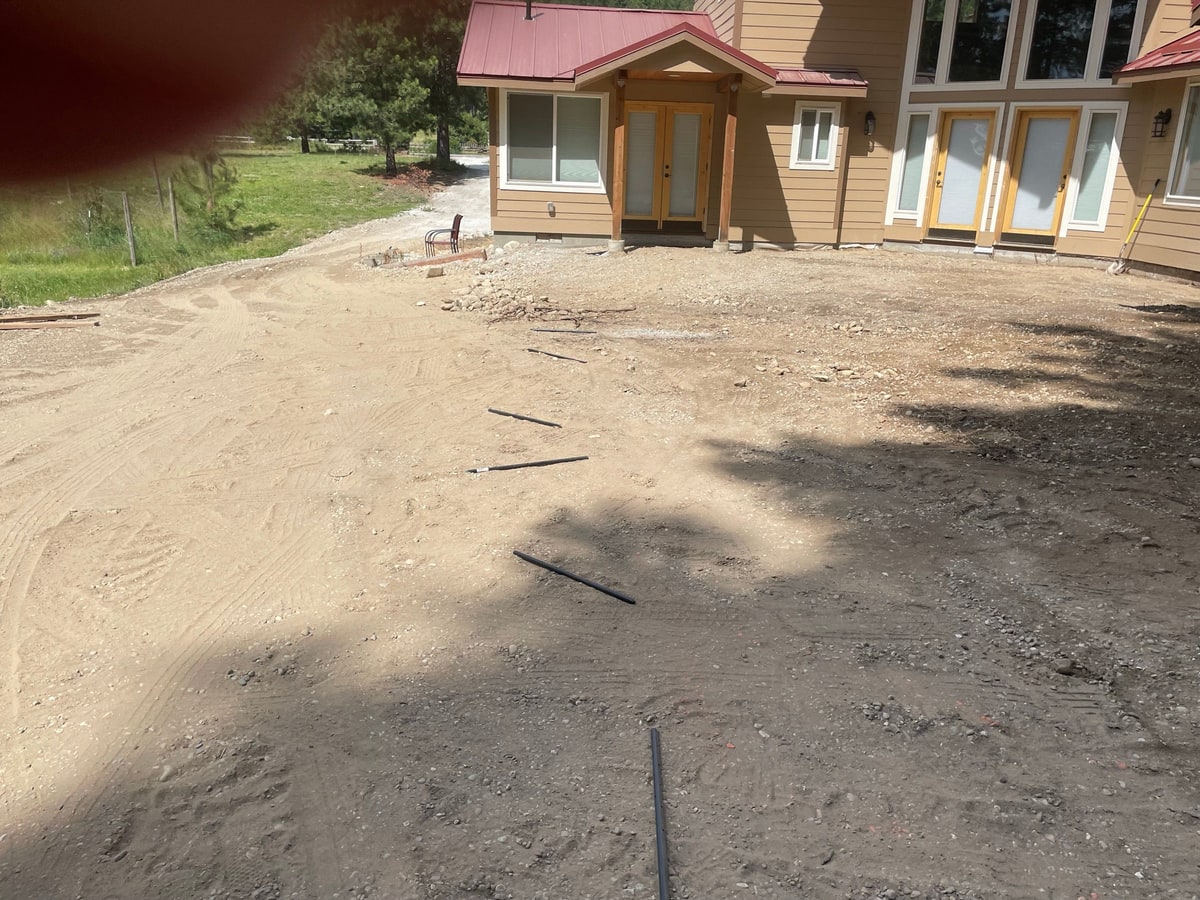 Graded dirt yard in front of the red-roofed house.
