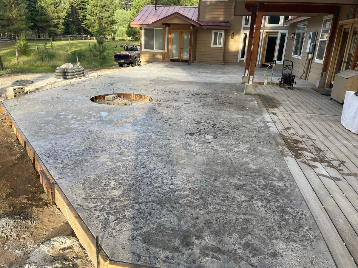 Large new patio with fire pit ring beside the house and deck.