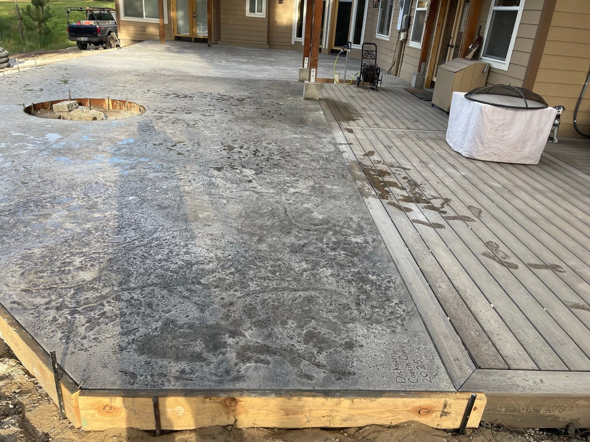 New patio with a fire pit ring beside the wooden deck.