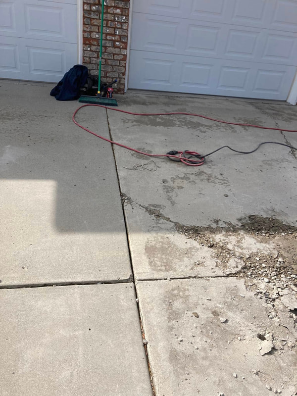 Old cracked driveway at the garage with a hose and cutter.