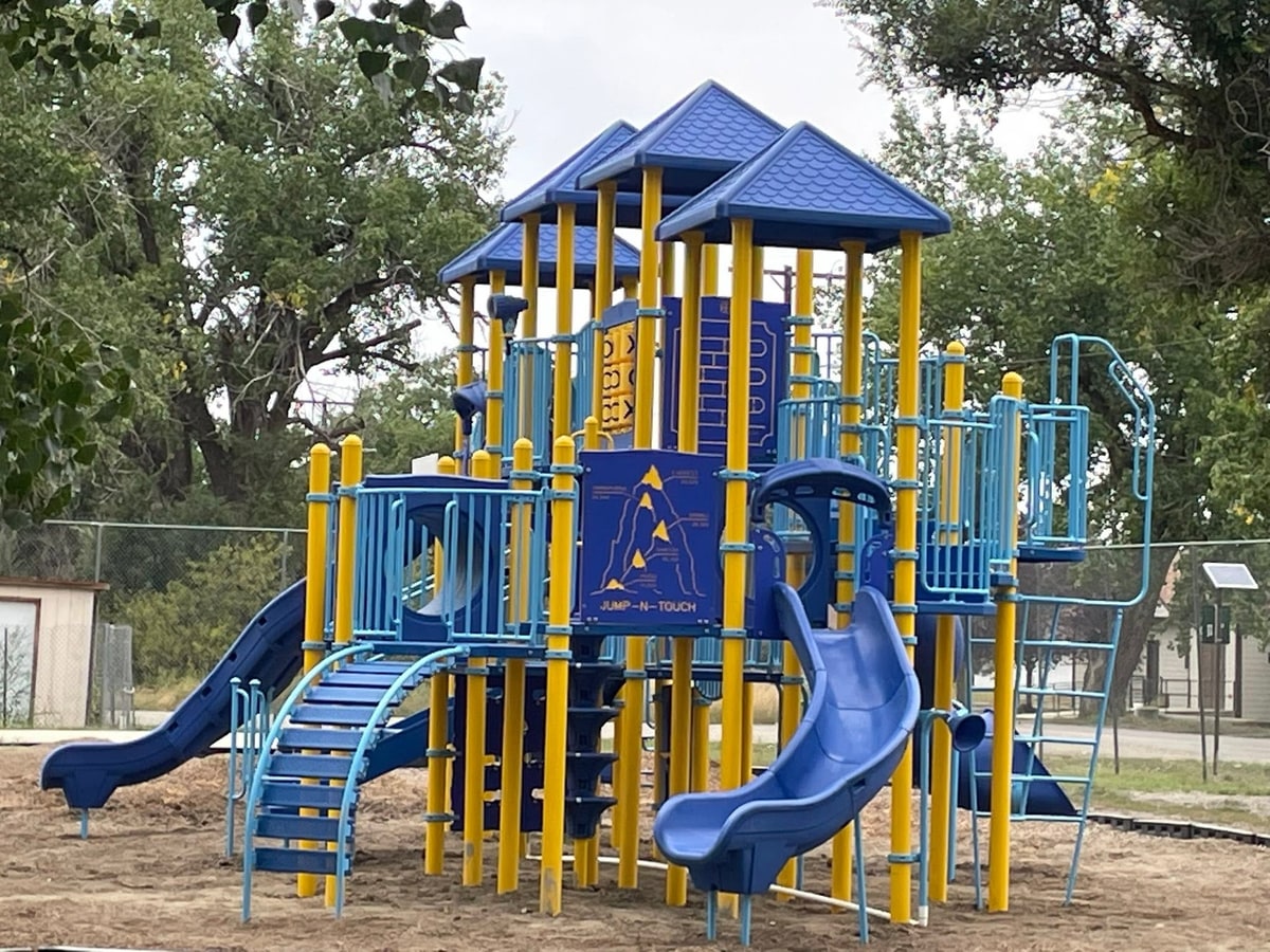 Blue and yellow tower with slides and a climbing wall panel.