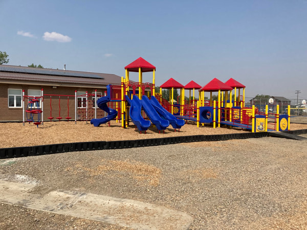 Row of red-roofed play towers on wood chips at a school.