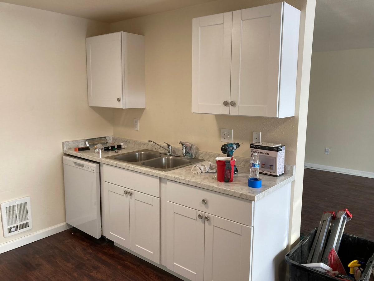 Remodeled kitchen with white shaker cabinets and a new dishwasher.