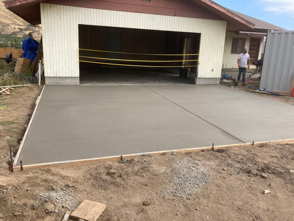 Crew finishing a garage slab with tape across the door.