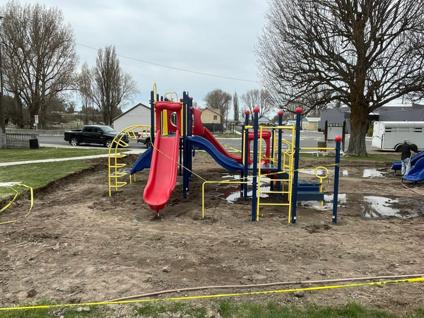 Play structure at a rural school with a truck and bare trees.