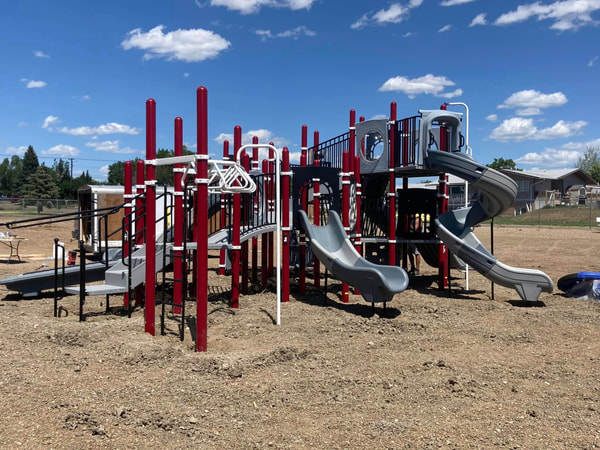 Grey and red play structure with slides at a school.